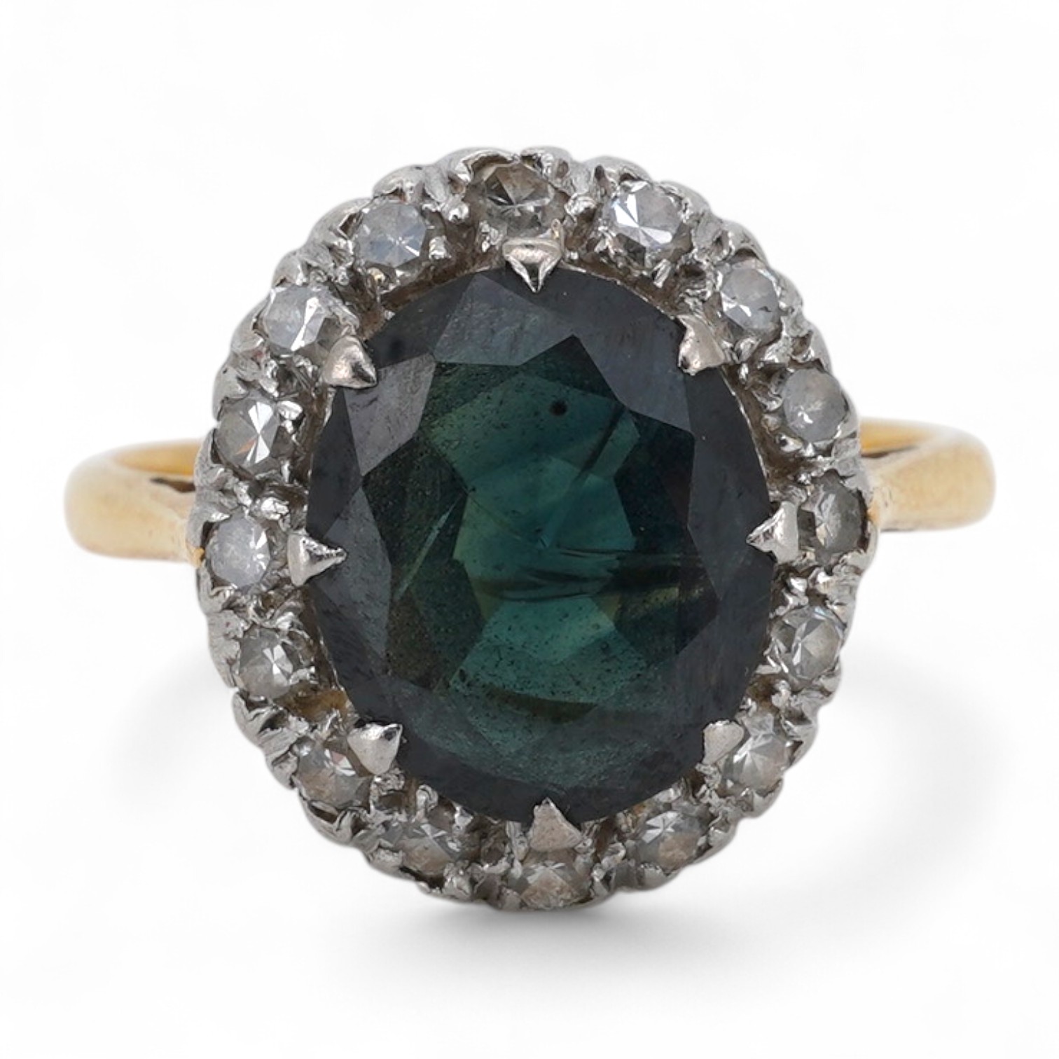A sapphire and diamond ring, of cluster design, set with a cushion-shaped sapphire weighing approximately 2.20 carats, within a border of single-cut diamonds totalling approximately 0.50 carats, mounted in gold and plati